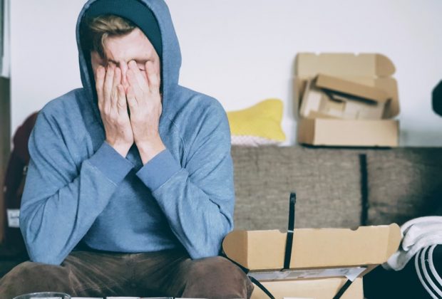 man covering face with both hands while sitting on bench